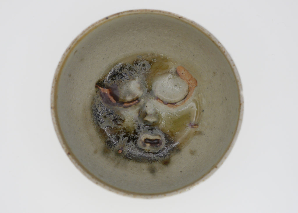 Ceramic bowl with abstract face design on a white background