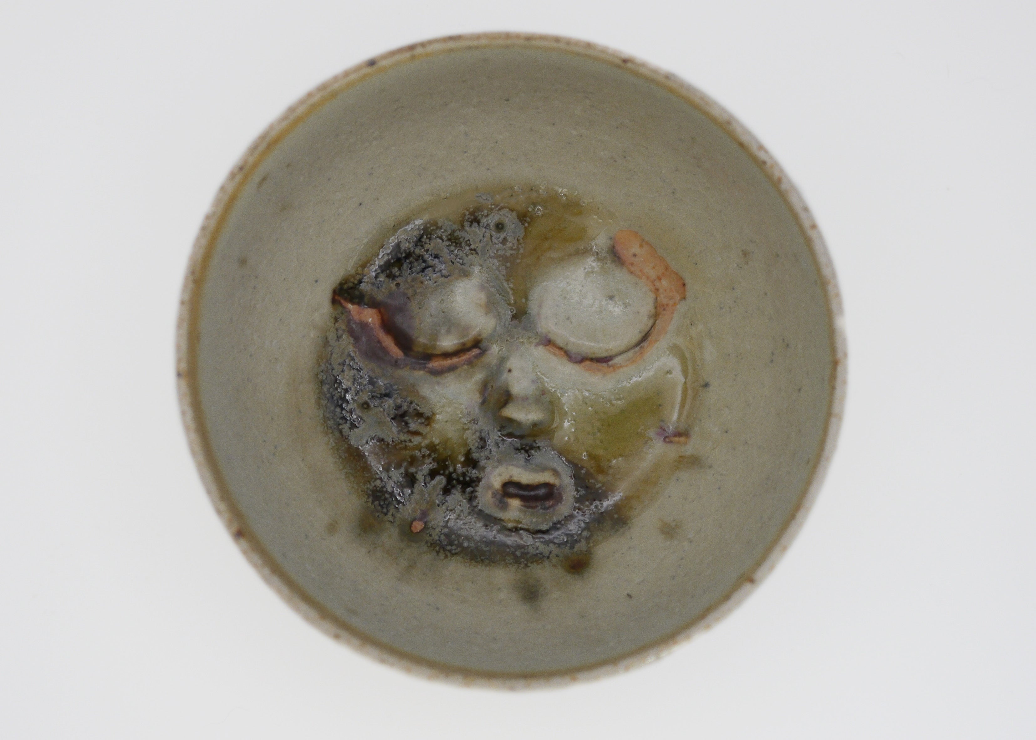 Ceramic bowl with abstract face design on a white background