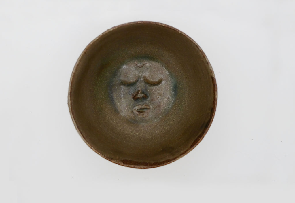 Ceramic bowl with face design on a white background