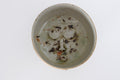 wood fired ceramic bowl with decorative face design on a white background