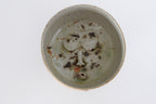 wood fired ceramic bowl with decorative face design on a white background